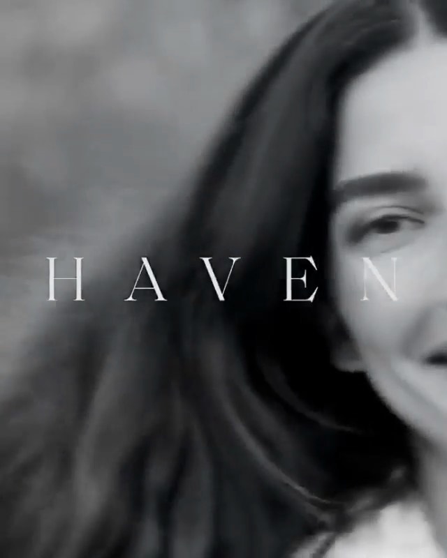 Monochrome portrait of a woman with long hair and a smile, featuring the word 'HAVEN' across the frame, creating an intimate and serene visual.