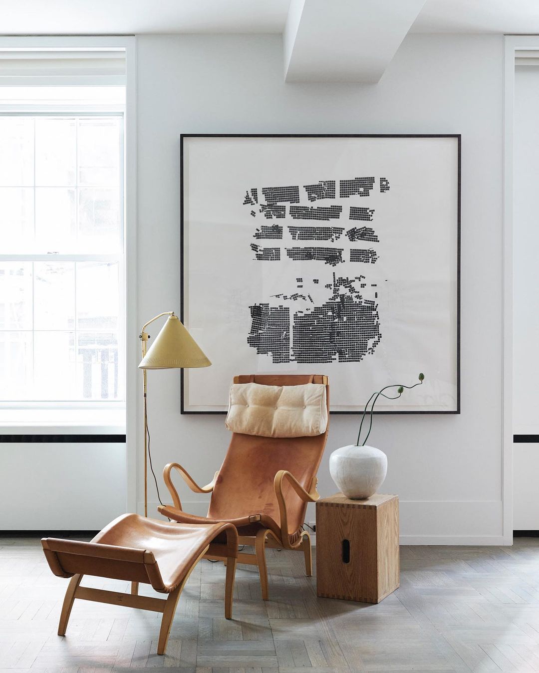 Tan leather lounge chair with ottoman and floor lamp in a white interior by Bjorn Wallander