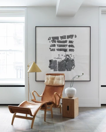 Tan leather lounge chair with ottoman and floor lamp in a white interior by Bjorn Wallander