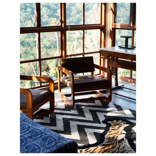 Indoor shot features two mid-century modern armchairs, wood-frame window, and rug with black-and-white chevron tiger stripe pattern.