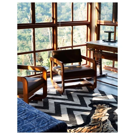 Indoor shot features two mid-century modern armchairs, wood-frame window, and rug with black-and-white chevron tiger stripe pattern.