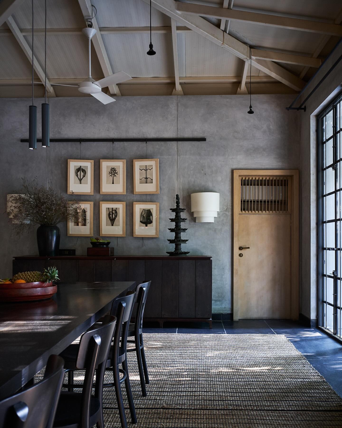 Interior design of a dining room with a long dark wood table, black chairs, and neutral color palette, creating an elegant and modern space.