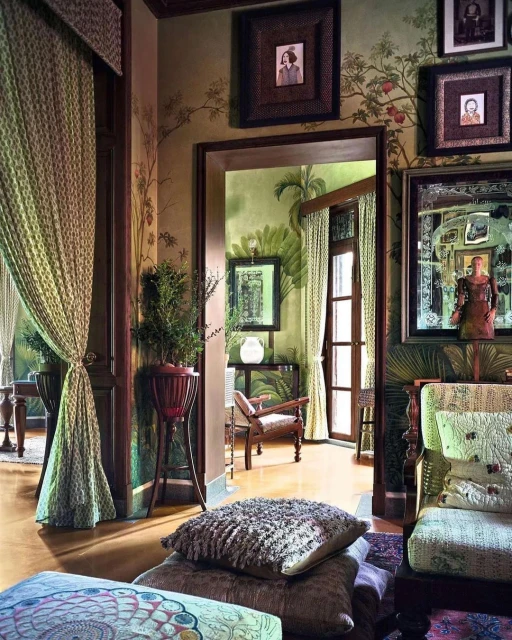Interior view of a room with decorative pillows, a potted plant, draped curtains, and framed artwork, creating an elegant living space.