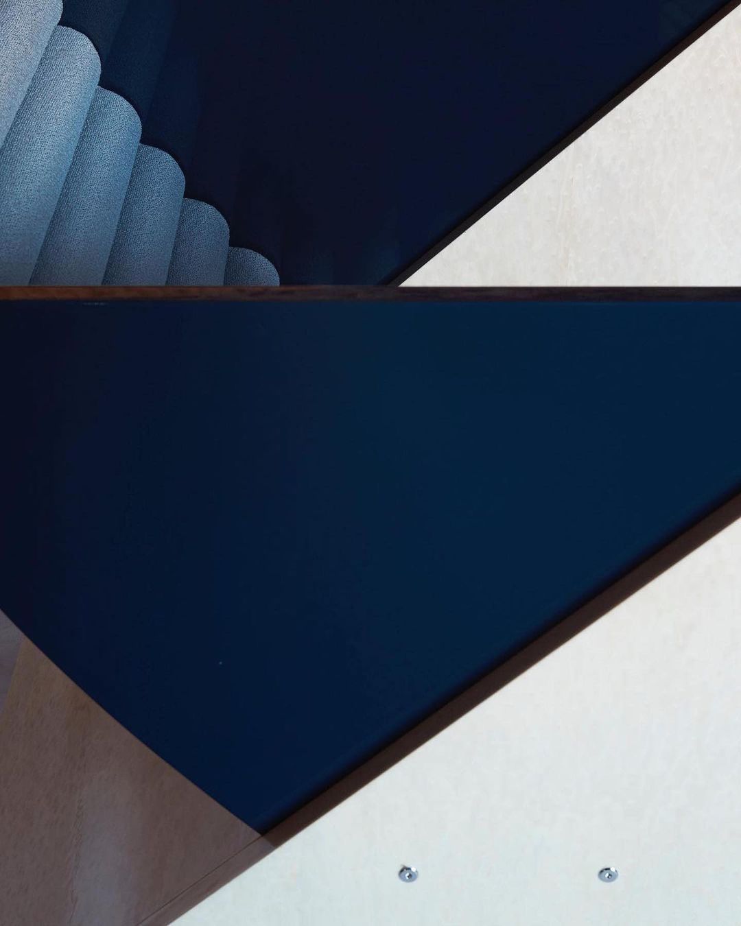 Abstract geometric pattern features dark blue panels alongside white and blue textured elements on a neutral surface. Modern design.