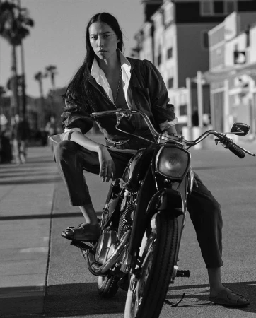 Black and white portrait of a woman seated on a vintage motorcycle on an urban street, photographed by Blair Getz Mezibov.