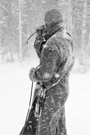 Person in winter coat with snow and climbing rope outdoors. Back view of outdoor apparel and gear in a snowy, forest environment.