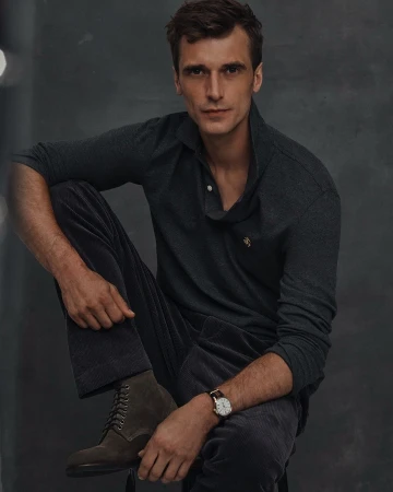 Man wearing a dark grey polo shirt and trousers sitting down, photographed by Blair Getz Mezibov in New York.