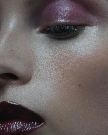 Close-up beauty portrait featuring a woman with glossy dark red lips and soft purple eyeshadow, photographed by Blair Getz Mezibov.