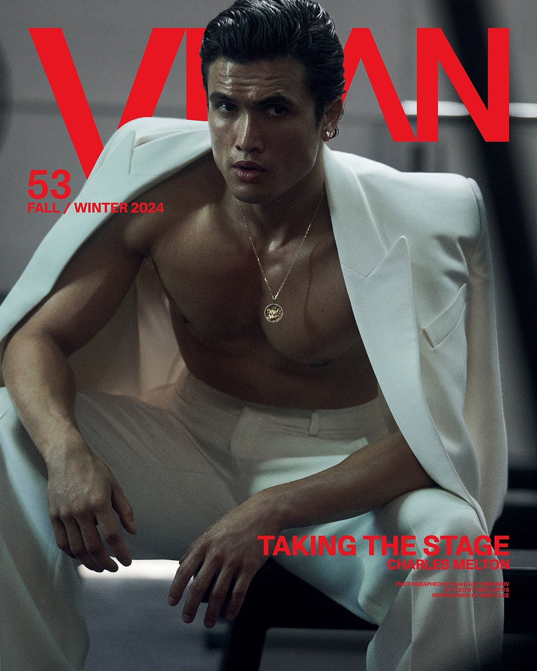 Magazine cover featuring a male fashion model in a white suit jacket and pants, posing with a serious expression indoors.