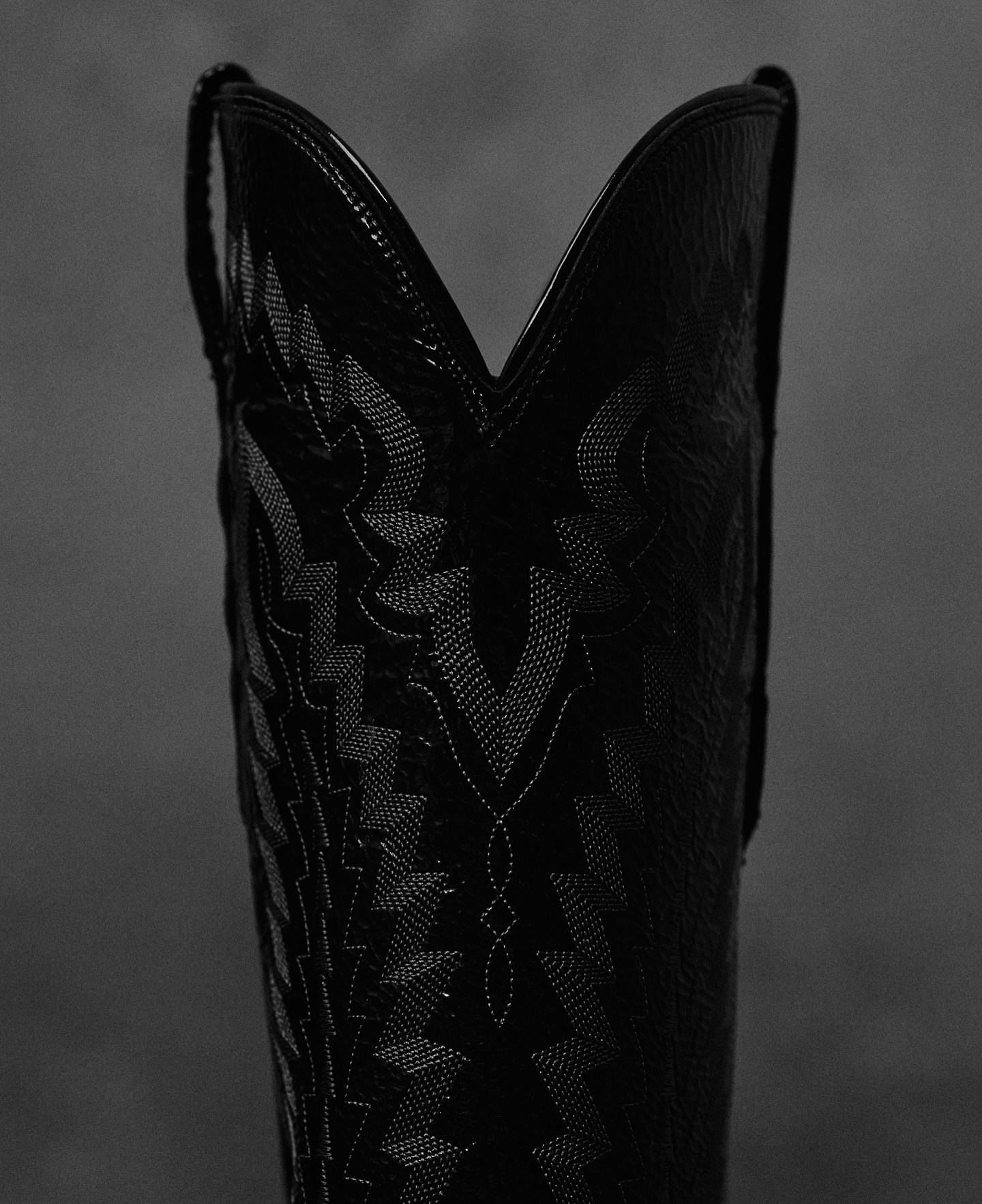 Close-up of a black cowboy boot with intricate stitching details; a high-fashion, stylish accessory with Western aesthetic.