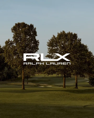 RLX Ralph Lauren logo displayed over a green golf course surrounded by trees on a sunny day with a clear blue sky.