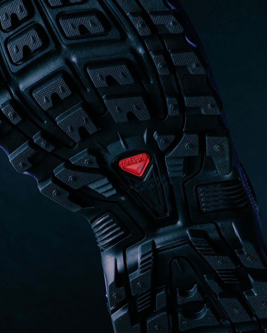 Close-up of the textured black rubber sole of a shoe with a red Contagrip logo, featuring a pattern of geometric shapes for traction.