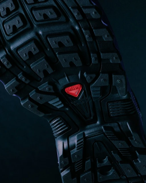 Close-up of the textured black rubber sole of a shoe with a red Contagrip logo, featuring a pattern of geometric shapes for traction.