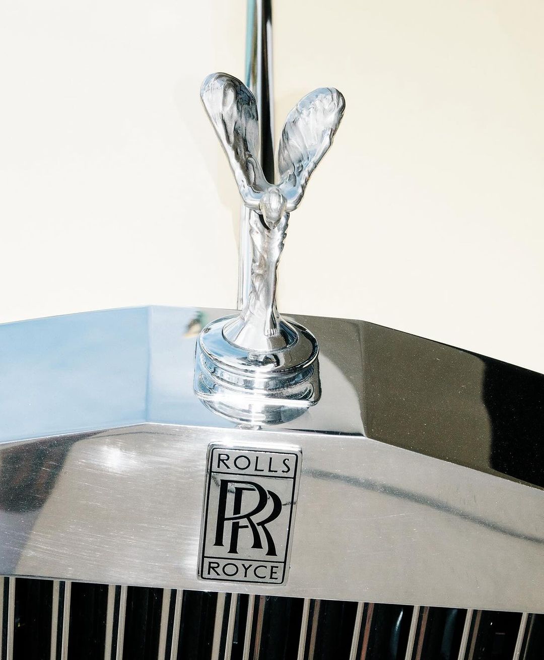 Close-up shot of a Rolls Royce automobile featuring the iconic Spirit of Ecstasy hood ornament, logo, and front grill.