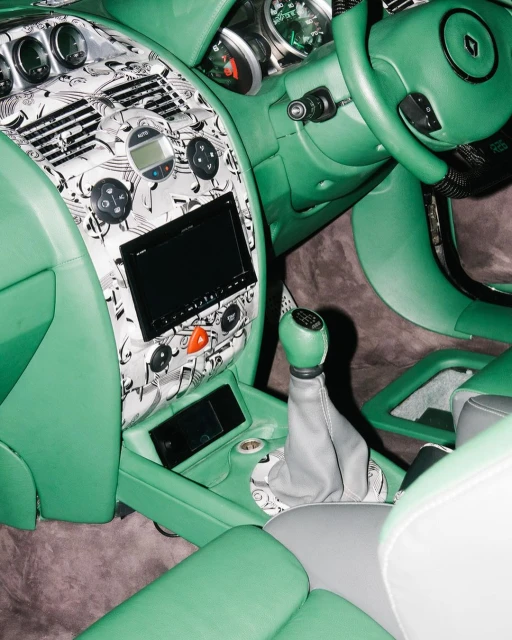 Car interior showcasing mint green leather upholstery, dashboard with music note pattern, gear shift, and steering wheel.