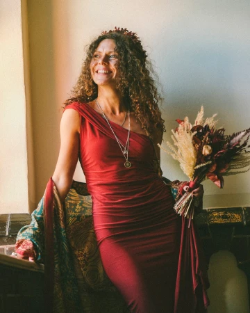 Woman in red one-shoulder dress holding a floral bouquet, photographed by Bob Sala.