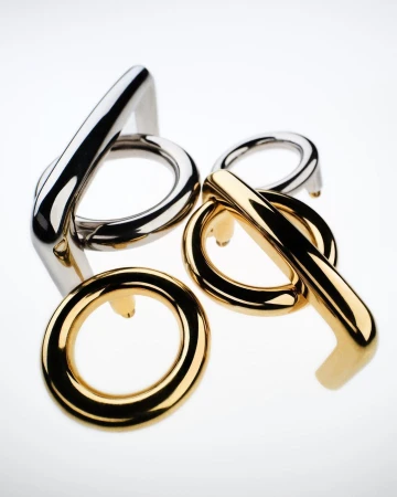 Abstract arrangement of gold and silver metal rings and bars with rounded edges, set against a stark white background with soft, diffused lighting.