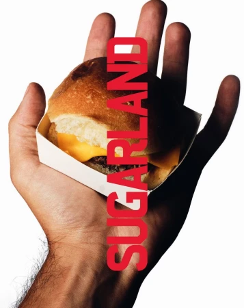 Close-up of a cheeseburger in a white cardboard container being held in a human hand, with red capitalized text overlay.