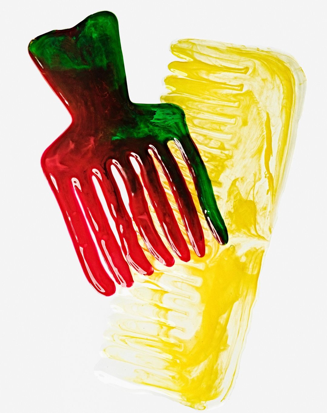 Abstract image of two decorative hair combs: one in red, green, and clear and the other in yellow with a white background.