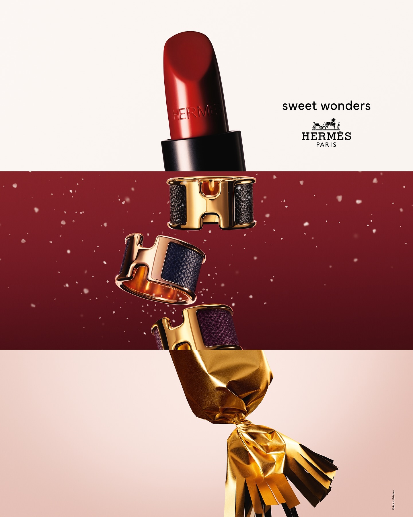 Hermès beauty product still life: lipstick, bracelets, and wrapped candy. Red, gold, and brown tones create a luxurious and festive mood.