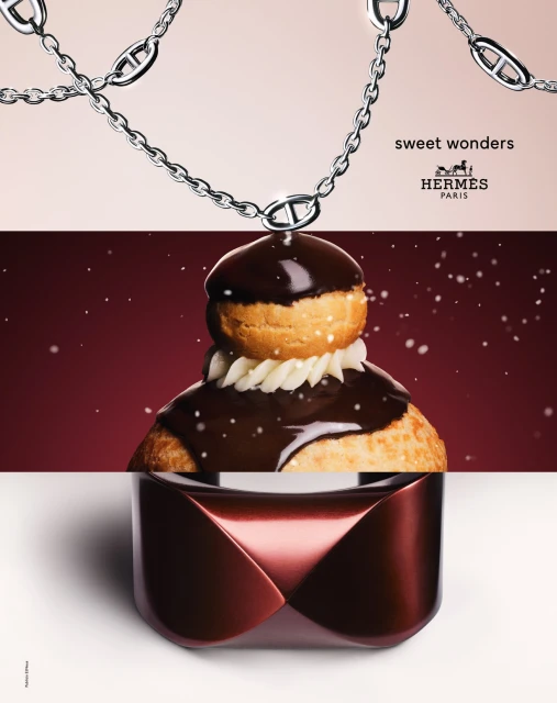 Still life shot of a Hermès chain necklace, cream-filled pastry with chocolate glaze, and perfume bottle against a gradient backdrop.