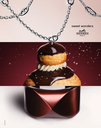 Still life shot of a Hermès chain necklace, cream-filled pastry with chocolate glaze, and perfume bottle against a gradient backdrop.