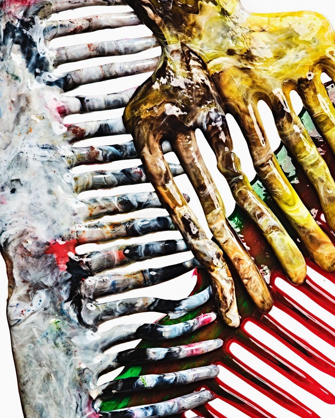 Close-up abstract photography of a glossy, resin-coated comb with dripping colorful paints in red, yellow, and green by Bobby Doherty