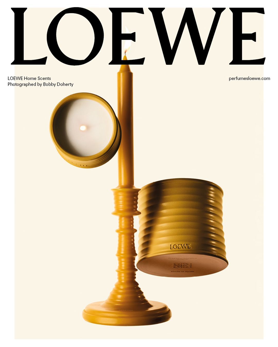 Still life featuring Loewe candles in yellow hues, showcasing a tall candle holder and scented candles against a bright background.