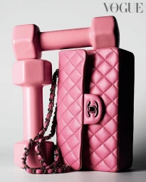 Pink quilted leather handbag with chain strap stacked beside a glossy pink dumbbell on a white background