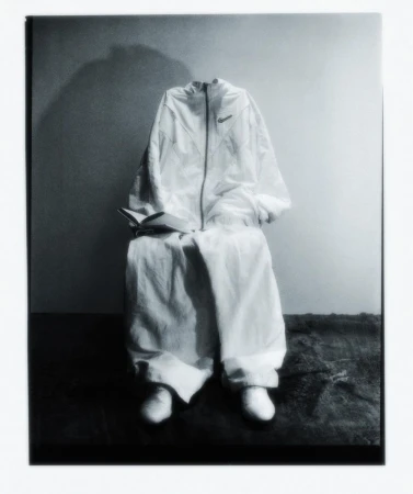 White athletic suit and shoes arranged on a chair against a two-tone background. The book adds a literary touch.