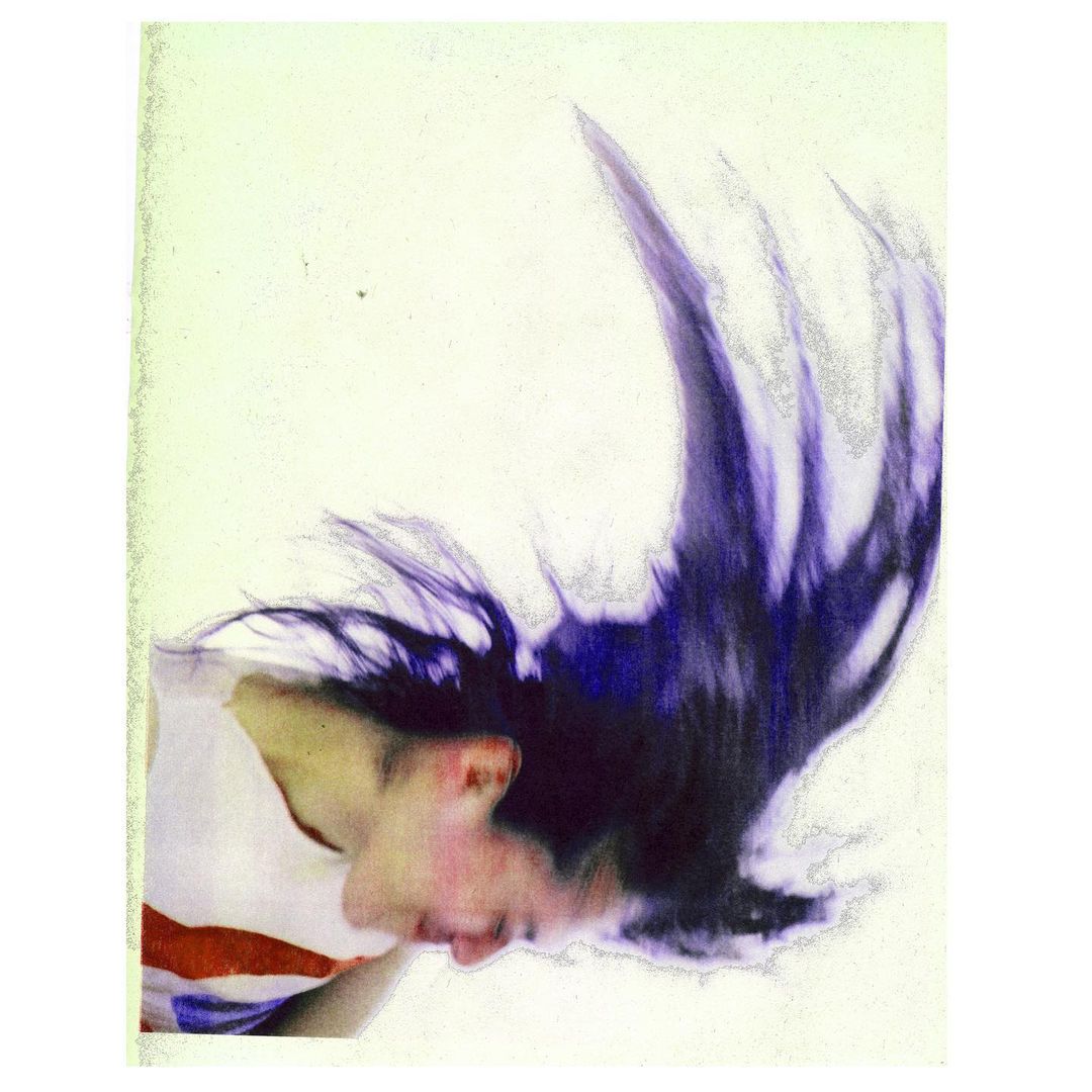 Abstract studio portrait of an adult female with long dark hair flipping, wearing a white t-shirt against a pale background with vintage effect.