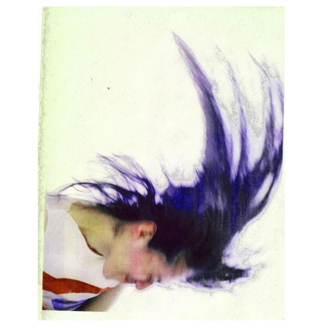 Abstract studio portrait of an adult female with long dark hair flipping, wearing a white t-shirt against a pale background with vintage effect.