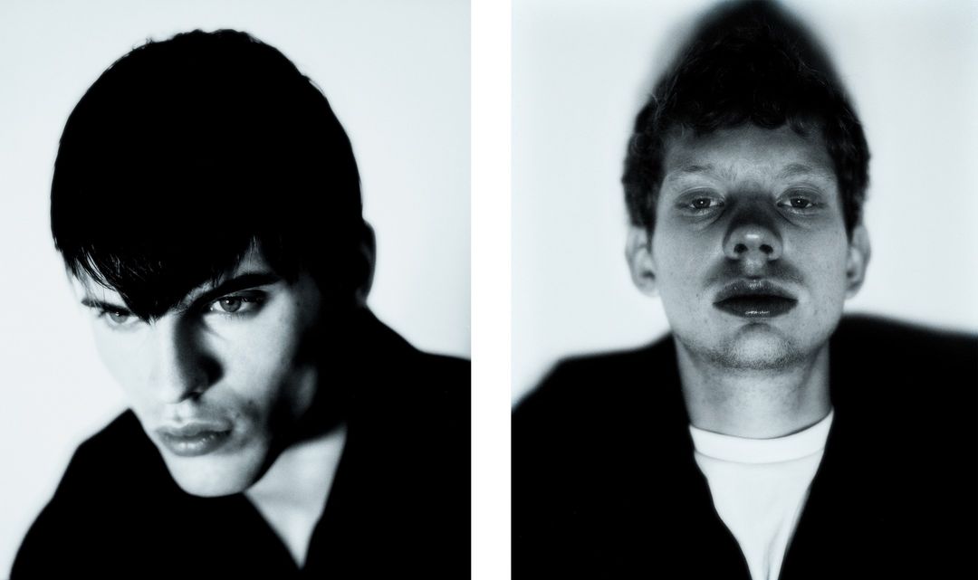 Two portraits of young adult men in black shirts against a white background, close-up, in black and white, studio lighting.