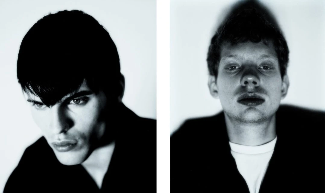 Two portraits of young adult men in black shirts against a white background, close-up, in black and white, studio lighting.