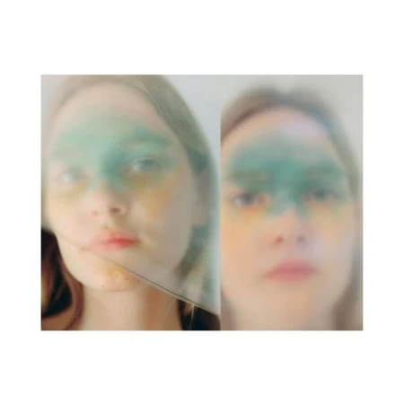 Artistic portrait of a fair-skinned young woman with green and yellow face paint, presented in a diptych against a white backdrop.