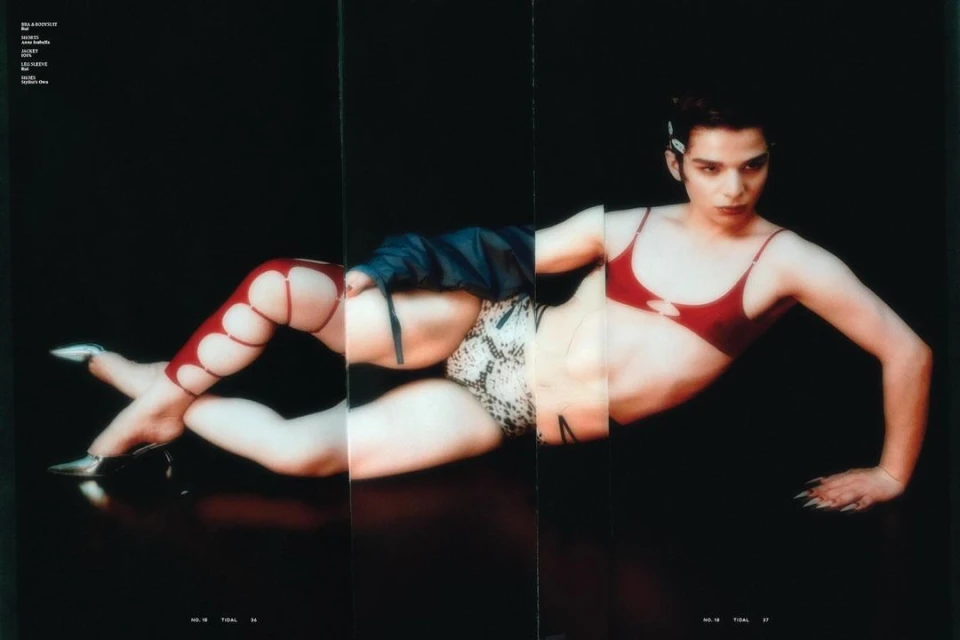 Woman in red bra and patterned underwear poses lying down in front of a dark background with retro, fashion editorial aesthetic.