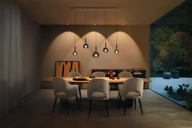 Dining room interior with a wooden table, six chairs, and pendant lights, featuring a modern design and neutral color palette.