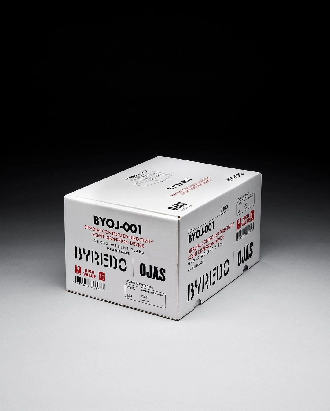 A white branded packaging box featuring black and red typography resting on a grey seamless studio backdrop.
