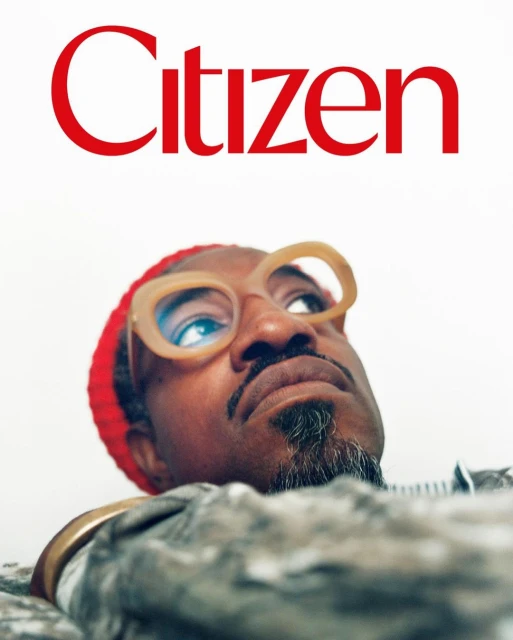 Close-up studio shot of African-American adult male wearing stylish glasses and red beanie, looking up with 'Citizen' text visible.