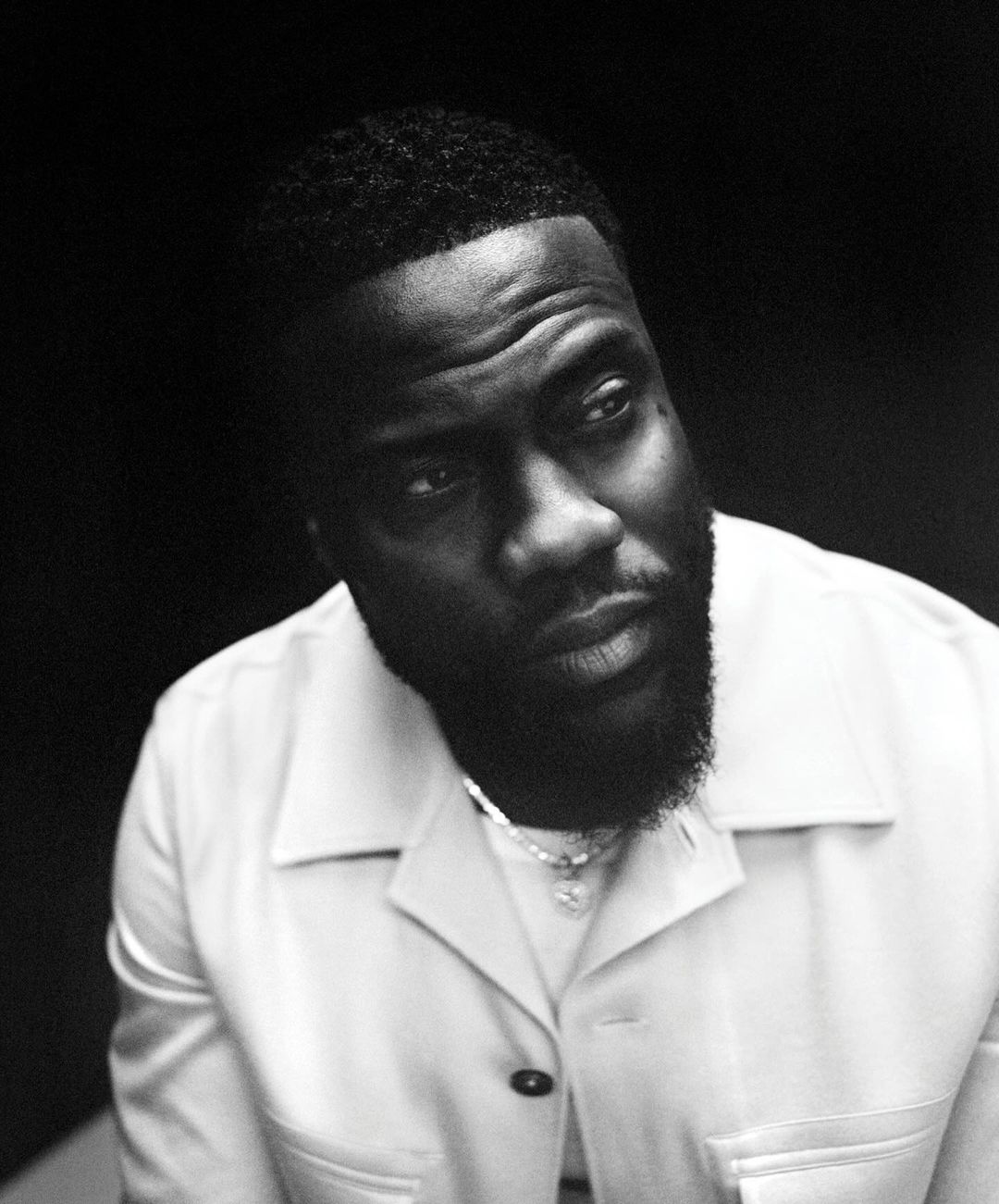 Monochrome portrait of a Black man with short hair and a beard wearing a collared button-up shirt by Bolade Banjo