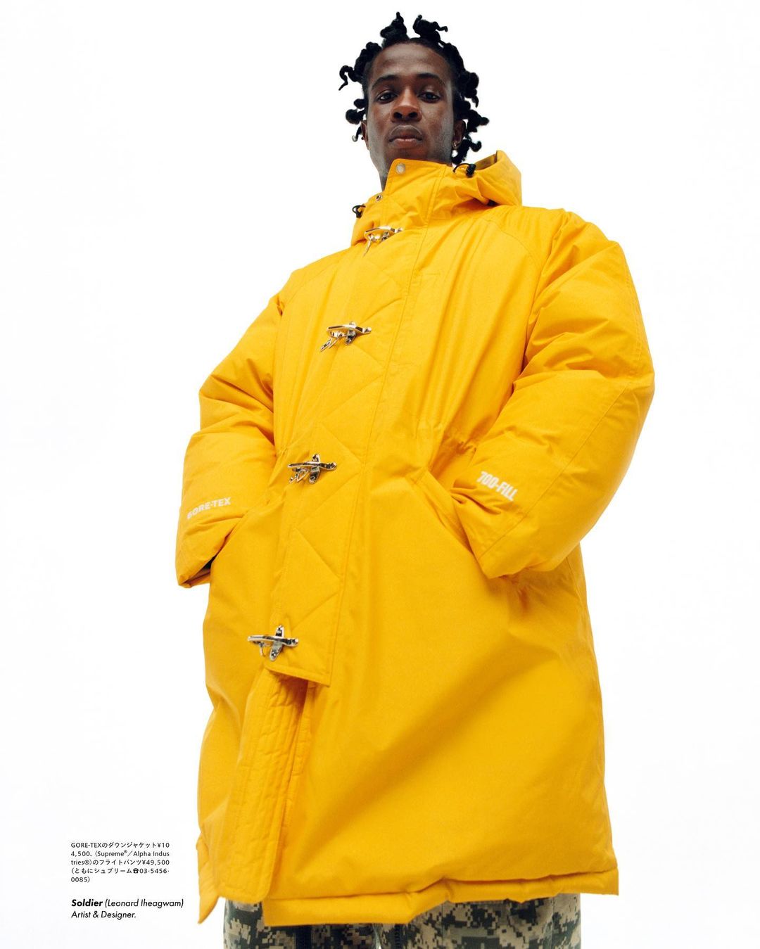 Man poses in a yellow puffer coat with toggles against a white backdrop, blending fashion and urban style with a striking color.