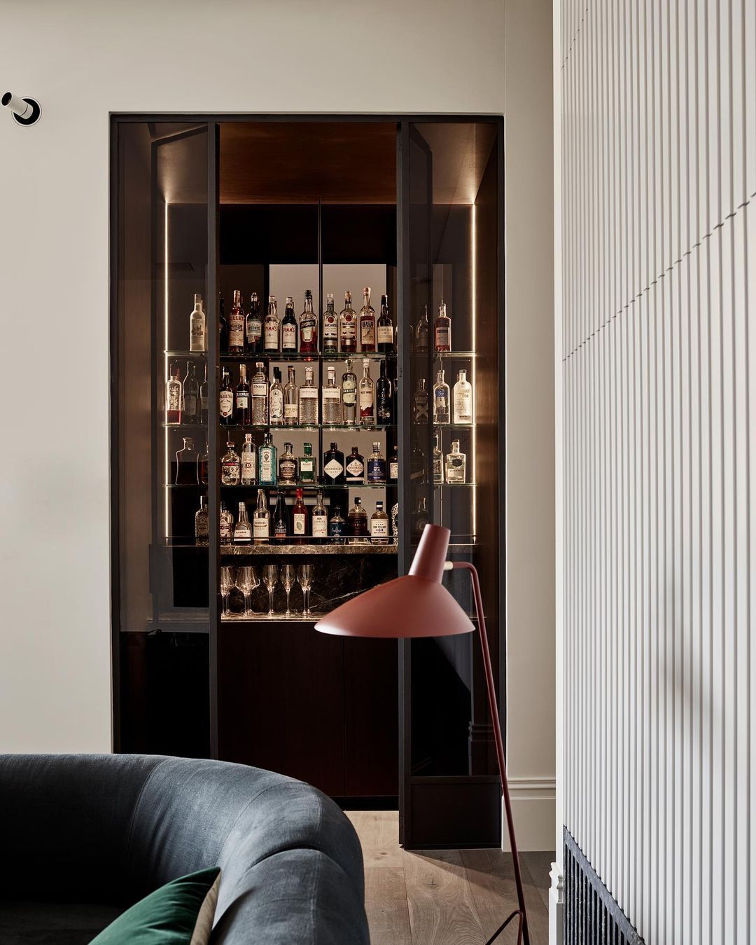 Interior view featuring a stylish home bar filled with assorted liquor bottles, complemented by a modern floor lamp and contemporary decor.