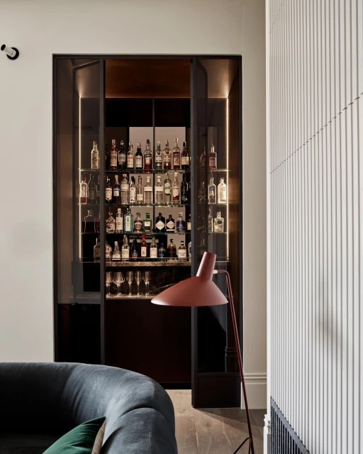 Interior view featuring a stylish home bar filled with assorted liquor bottles, complemented by a modern floor lamp and contemporary decor.