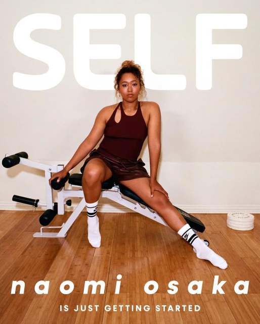 Naomi Osaka sits on a workout bench in a fitness photoshoot for Self Magazine. The workout is in a light-filled indoor setting.