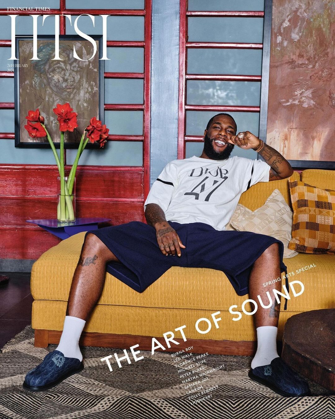 Magazine cover featuring a Black adult male reclining on a yellow couch in a relaxed pose, wearing casual clothing, set in an indoor environment.
