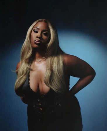 Portrait of a woman with blonde hair wearing a black top against a dark blue spotlight background by Brandon Hicks