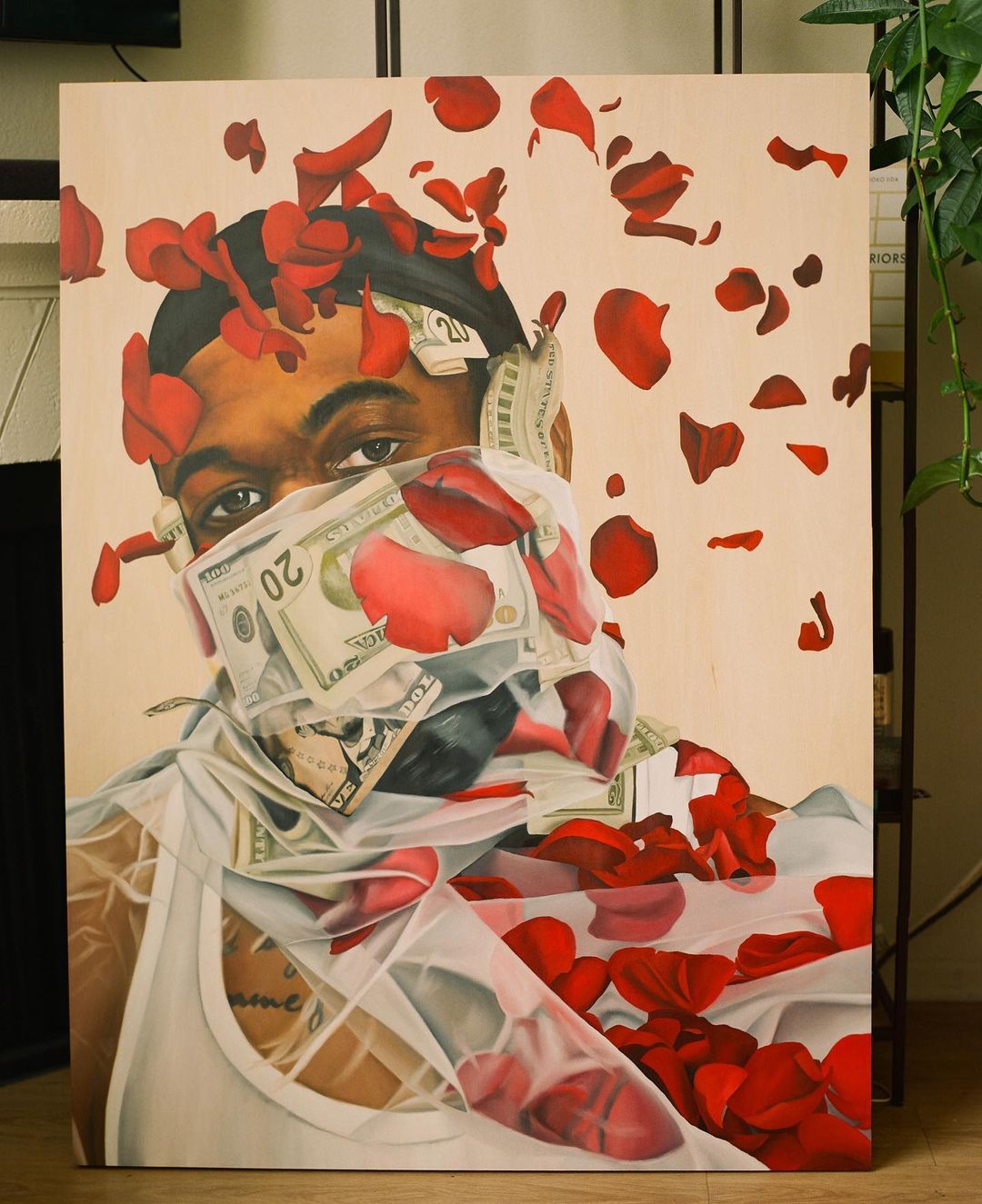 Painted portrait of a person obscured by rose petals and money, creating a surreal and visually striking image with a tan background.