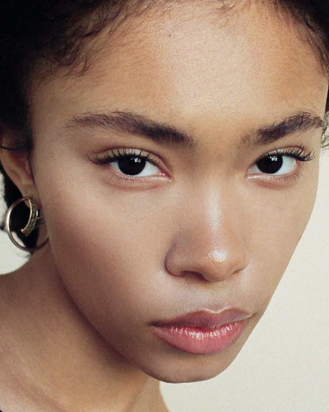 Close up portrait of a young woman with natural skin tones wearing a silver hoop earring, photographed by Brandon Hicks.