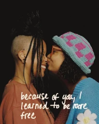 Two women close together in profile against a dark background, one wearing a blue patterned bucket hat and cardigan.
