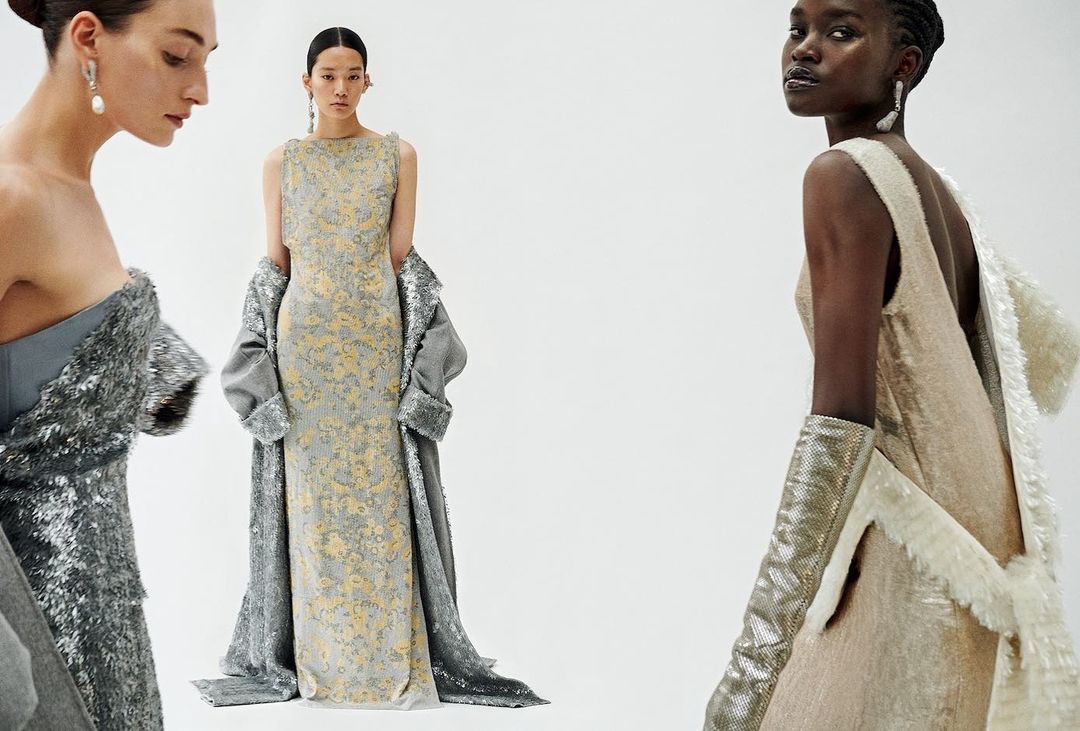Three women in elegant gowns pose against a white backdrop. One woman wears a silver sequin dress, another a floral gown with a coat, and the third a sleeveless gown with gloves.